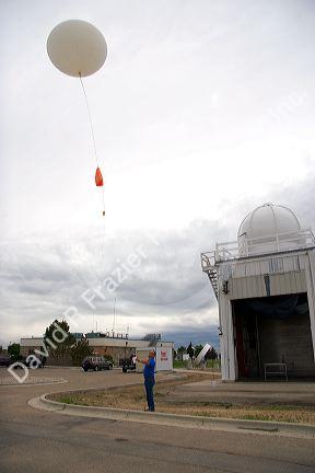 Meteorologist launching a weather balloon with a radiosonde sensor at the National Weather Service in Boise, Idaho.