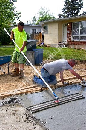 Workers leveling a newly poured concrete driveway in Boise, Idaho.