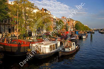 Boats docked along the Amstel River in Amsterdam, Netherlands.