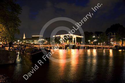 Skinny Magere drawbridge lit up at night on the Amstel River in Amsterdam, Netherlands.