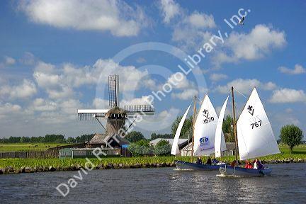 Sailing past a windmill on a canal east of Leiden in the province of South Holland, Netherlands.