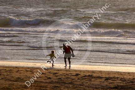 Father and daughter play in the surf of the North Sea at sunset in the Netherlands.