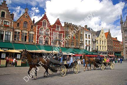 Horse drawn carriages in The Big Market Square at Bruges in the province of West Flanders, Belgium.