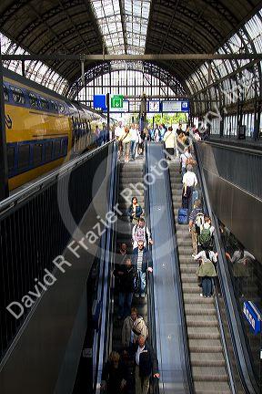 Passengers ride escalators and await trains at Amsterdam Central Station, Stationsplein, Amsterdam, Netherlands.