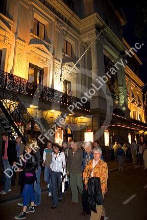 People on the street in front of the Royal Carre Theatre at night in Amsterdam, Netherlands.