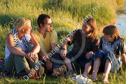 A family sits at sunset near Le Mont Saint Michel in the region of Basse-Normandie, France.