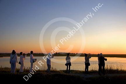 Tourists take photos of Le Mont Saint Michel at sunset in the region of Basse-Normandie, France.