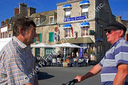 French men talking on the street in the village of Barfleur in the region of Basse-Normandie, France.