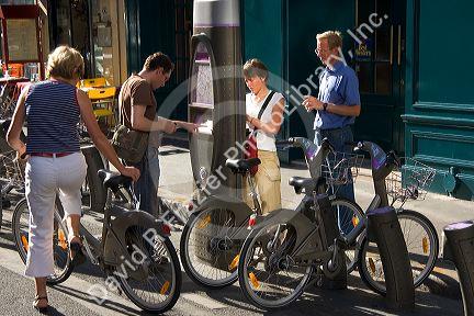 People using a Velib muni-meter to rent bicycles that are a part of the bike transit system in Paris, France.