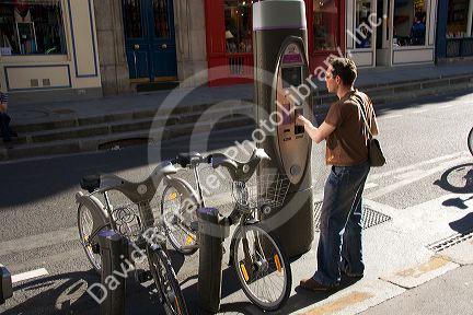 Man using a Velib muni-meter to rent a bicycle that is part of the bike transit system in Paris, France.