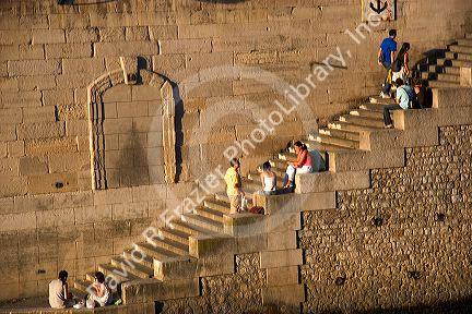 People sit on stone steps along the river Seine in Paris, France.