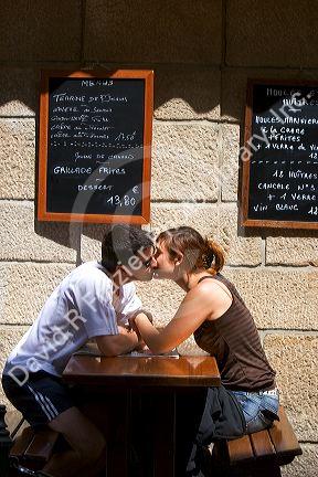 Young couple kissing at a sidewalk cafe in Saint-Malo in Brittany, northwestern France.