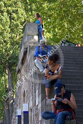 People sit on stone steps along the river Seine in Paris, France.