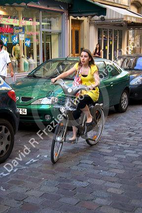 Young woman riding a rental bicycle that is a part of the Velib bike transit system in Paris, France.
