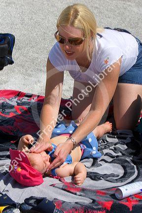 Mother applying sunscreen to her infant daughter at the beach in St. Petersburg, Florida. MR