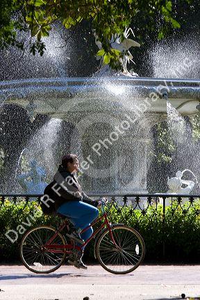 Bicyclist rides past a large water fountain in Forsyth Park in the historic district of Savannah, Georgia.