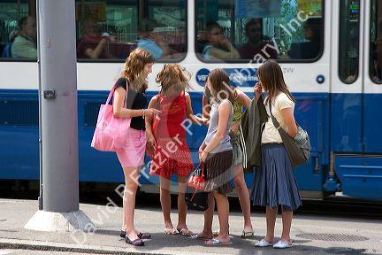 Teen girls stand at a trolley stop in Zurich, Switzerland.switzerland, swiss, europe, european, travel, tourism, swiss alps, alps, alpine, girls, teens, teenagers, sidewalk, zurich, trolley stop