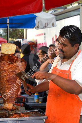 Street vendor cooking and cutting meat for soulvaki in Mexico City, Mexico.