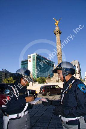Female police officers write a traffic ticket in front of the Angel de la Independencia in Mexico City, Mexico.