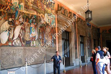 A tour guide showing tourists a mural painted by Diego Rivera at the National Palace in Mexico City, Mexico.