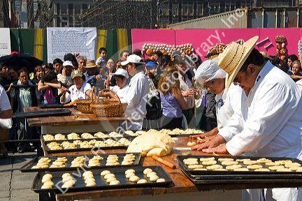 Bread being made in the shape of a skull to be givin away to the crowd of people celebrating Day of the Dead in the Zocalo in Mexico City, Mexico.