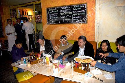 Mexican family eating pizza at a sidewalk cafe in Mexico City, Mexico.