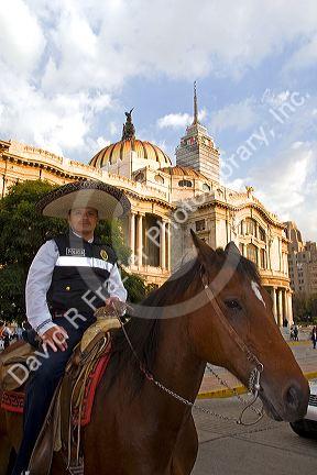 A police officer wearing a sombrero on horseback in front of the Palace of Fine Arts in Mexico City, Mexico.