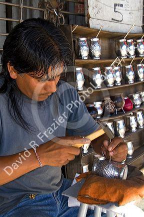 Street vendor engraving on a silver mate cup in Buenos Aires, Argentina.