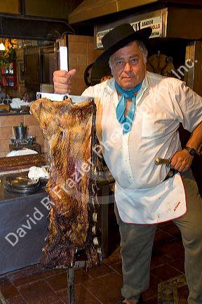 Argentine man cooking beef at a restaurant in Buenos Aires, Argentina.
