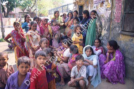 Indian women and children await a milk delivery in New Delhi, India.