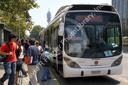 An articulated bus is part of the Transantiago public transport system picks up passengers at a bus stop in Santiago, Chile.