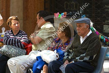 People sit on a bench on the Paseo Ahumada in Santiago, Chile.