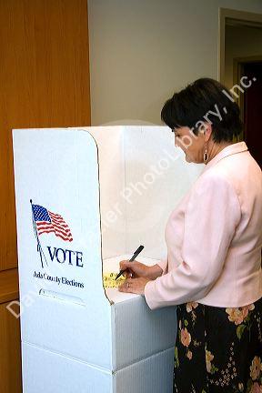 Woman voting on a paper ballot in a cardboard voting booth in Boise, Idaho.