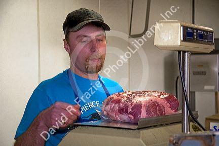Butcher weighing a pork roast at a butcher shop in Boise, Idaho. MR