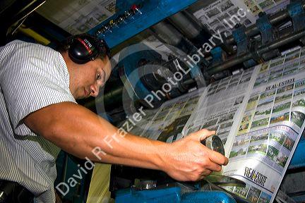 Pressman fin tunes newspaper being printed on a rotary printing press for the Houston Chronicle in Houston, Texas.