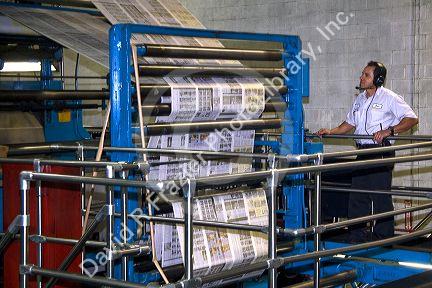 Pressman inspects newspapers being printed on a rotary printing press for the Houston Chronicle in Houston, Texas.