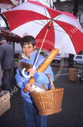 A french woman shopping in the rain with an umbrella in Paris, France.