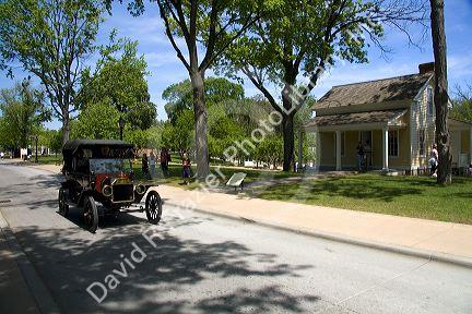 Ford Model T driving past the Chapman House in Greenfield Village at The Henry Ford in Dearborn, Michigan.
