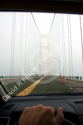 View from the inside of a car crossing the Mackinac Bridge on a foggy day in Michigan.