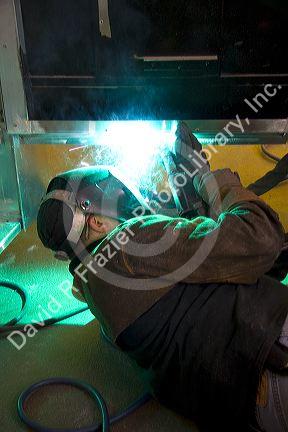 Worker Heliarc welding an aluminum truck chassis at Spartan Motors manufacturing plant in Charlotte, Michigan.