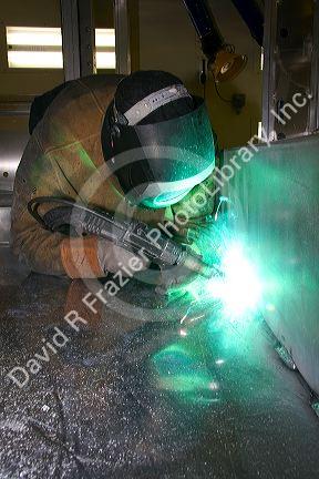 Worker Heliarc welding an aluminum truck chassis at Spartan Motors manufacturing plant in Charlotte, Michigan.