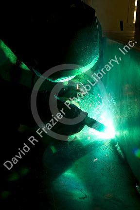 Worker Heliarc welding an aluminum truck chassis at Spartan Motors manufacturing plant in Charlotte, Michigan.