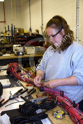 Female worker with wiring harness assembly at Spartan Motors truck chassis manufacturing in Charlotte, Michigan.