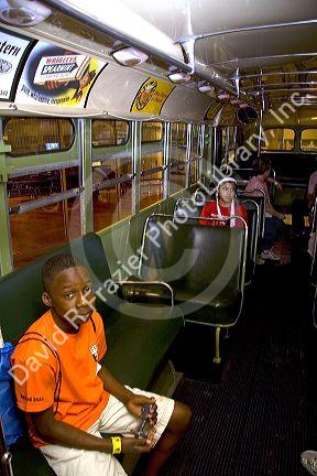 Black boy sitting in Rosa Parks city bus seat on display at The Henry Ford Museum in Dearborn, Michigan.
