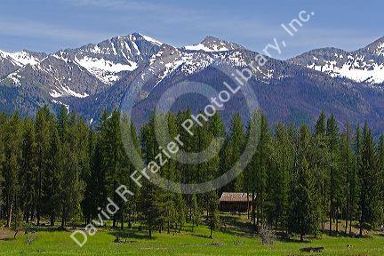 Log cabin sits below the Rocky Mountains near Condon, Montana.