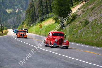 Classic American cars traveling over the high mountain Teton Pass on Wyoming Highway 22 near the state border of Wyoming and Idaho.