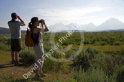 Tourists view the Teton Range and Jackson Lake with binoculars in Grand Teton National Park, Wyoming.