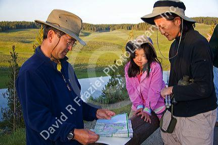 Asian family mapping out their visit to Yellowstone National Park, Wyoming. MR