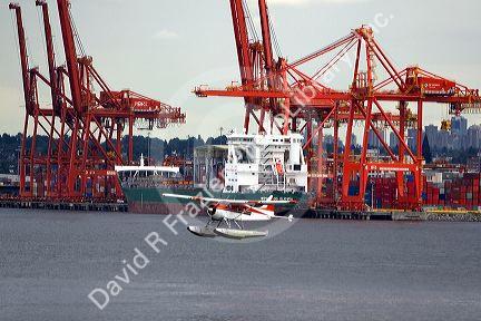 Seaplane taking off in front of a container ship at Port Vancouver in British Columbia, Canada.