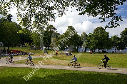 Bicyclists ride along the Seawall path in Stanley Park at Vancouver, British Columbia, Canada.